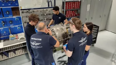Alumnos junto a un instructor trabajando sobre un motor. Foto: Aviation Group