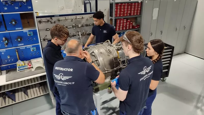 Alumnos junto a un instructor trabajando sobre un motor. Foto: Aviation Group